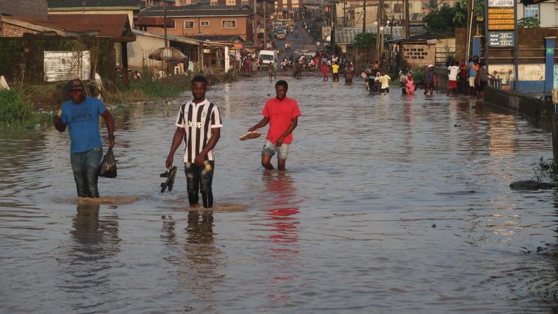 Residents walk along a flooded street in Aporu, Lagos, after heavy rain at 6