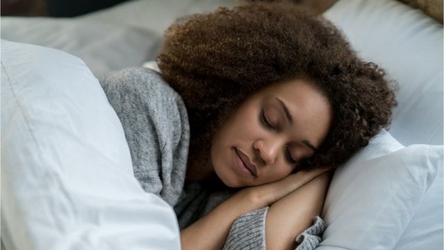 The photo shows a young woman sleeping in bed.