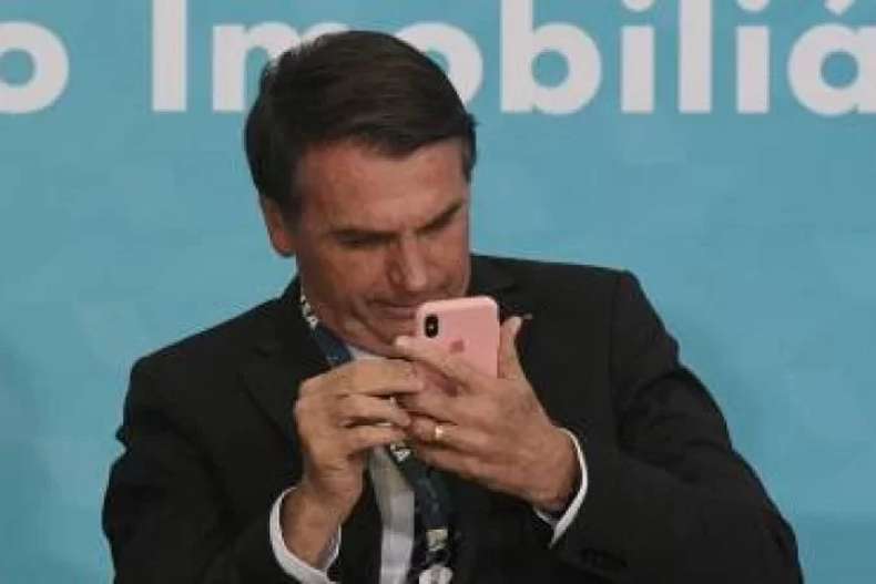 President Jair Bolsonaro (PL) holds a cell phone in his hands